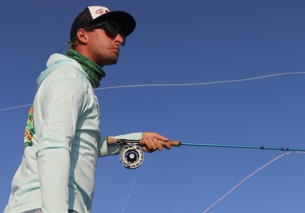 Alt text for flats fisherman casting fly fishing: A skilled angler casting a fly fishing line on a calm and shallow flat, surrounded by serene waters and mangroves.
