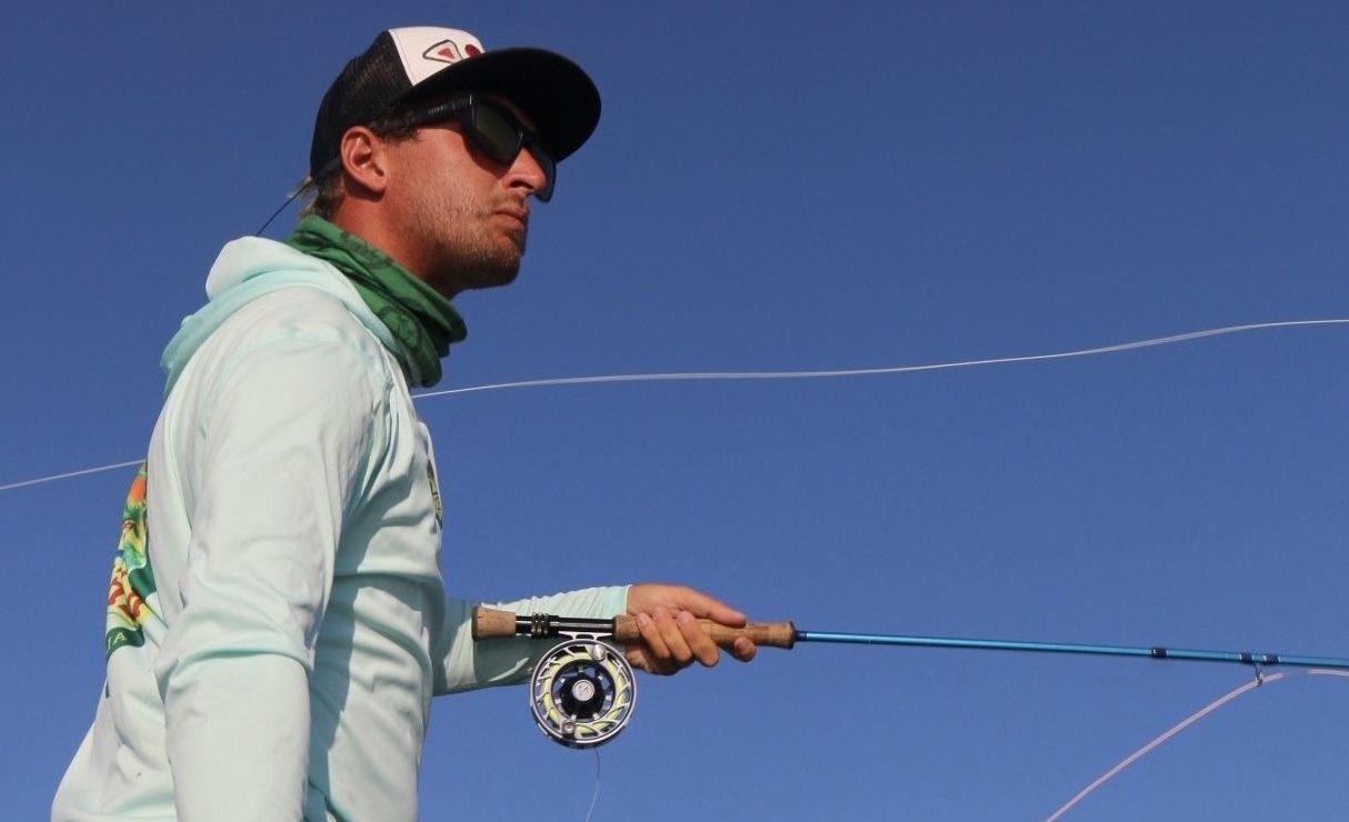 A skilled angler casting a fly fishing line, surrounded by waters and mangroves.