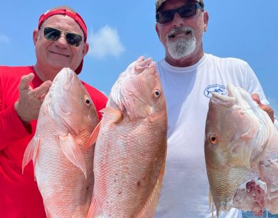 Two friends holding a mutton snapper partially eaten by a shark during a fishing charter in the Florida Keys.