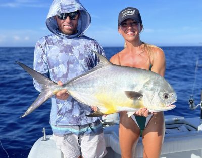 A couple holding a permit fish on a sunny day during a fishing charter.
