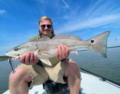 A man proudly holding a redfish he caught during a flats fishing charter in Florida.