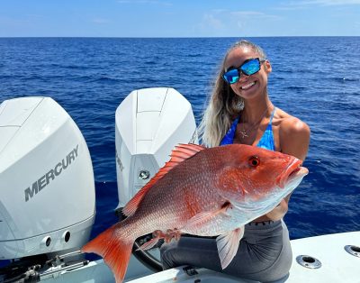 Young woman holding up red snapper, while on a fishing charter in Florida.