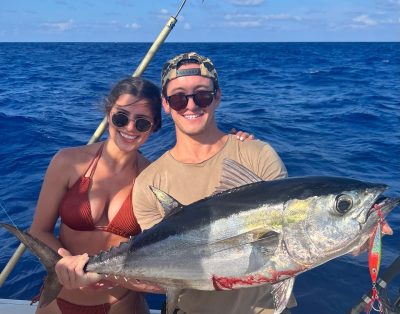 A couple holding a blackfin tuna during a sunny day fishing charter in Miami, Florida.
