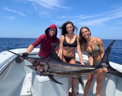 Three friends proudly display a swordfish they caught during a deep-sea fishing trip.