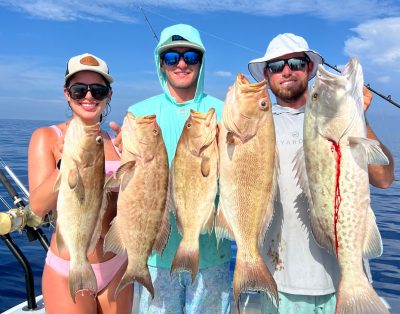 A group of friends holding up a scamp grouper caught while on a fishing charter in Dry Tortugas.