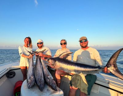 A group of four friends proudly displaying wahoos and swordfish after an incredible fishing charter in the Florida Keys.