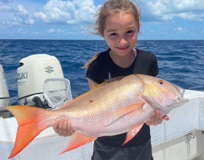 A young girl holding a mutton snapper during a family-friendly fishing charter in North Carolina's Outer Banks.