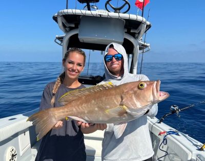 A couple holding a yellowedge grouper caught while deep dropping in the Florida Keys during a charter trip.