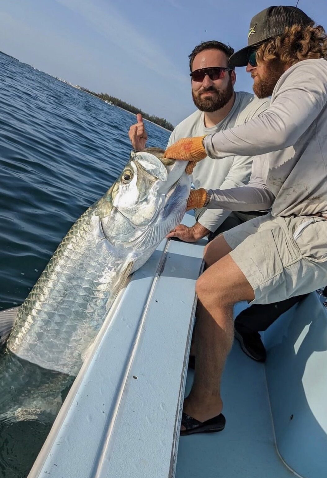 A group of friends fighting a tarpon while on a fishing charter amidst the scenic waters of Key West, Florida.