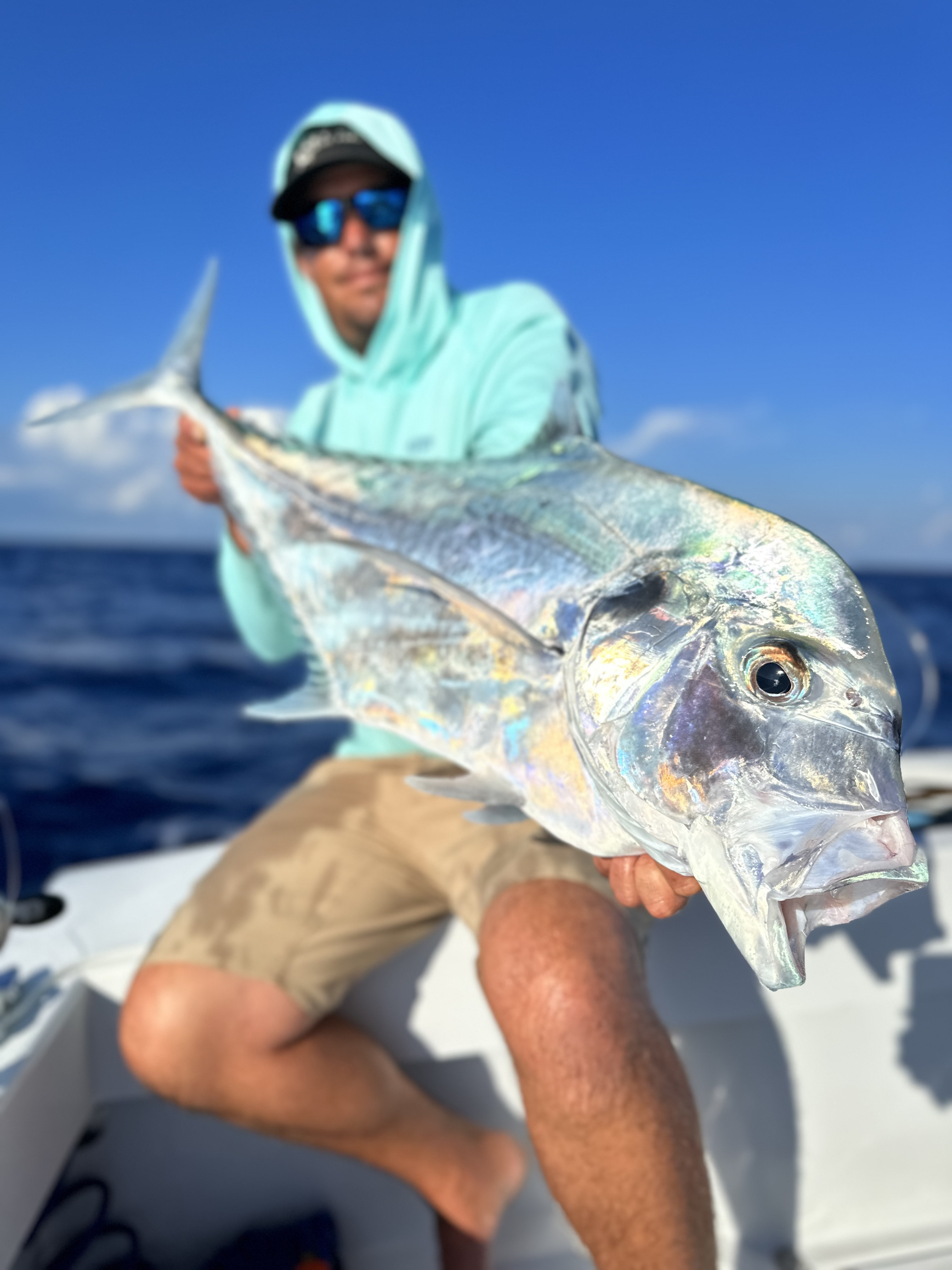 A angler holds up a large African Pompano caught during a fishing charter off the coast of Florida, showcasing the thrill of deep-sea fishing adventures.
