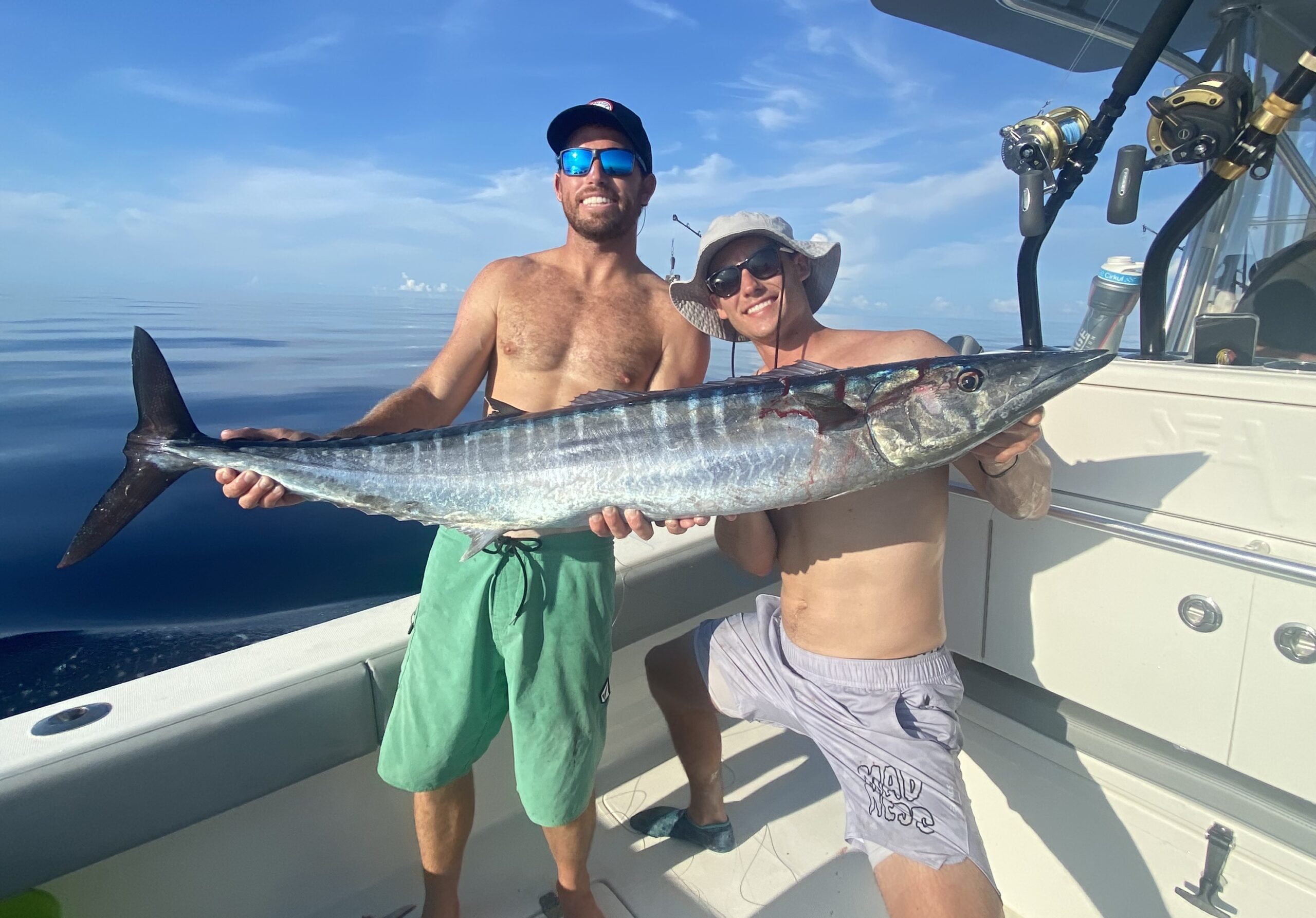 Two men proudly displaying their freshly caught wahoo fish against the scenic backdrop of Key West, Florida, epitomizing the thrill and success of wahoo fishing in the region.