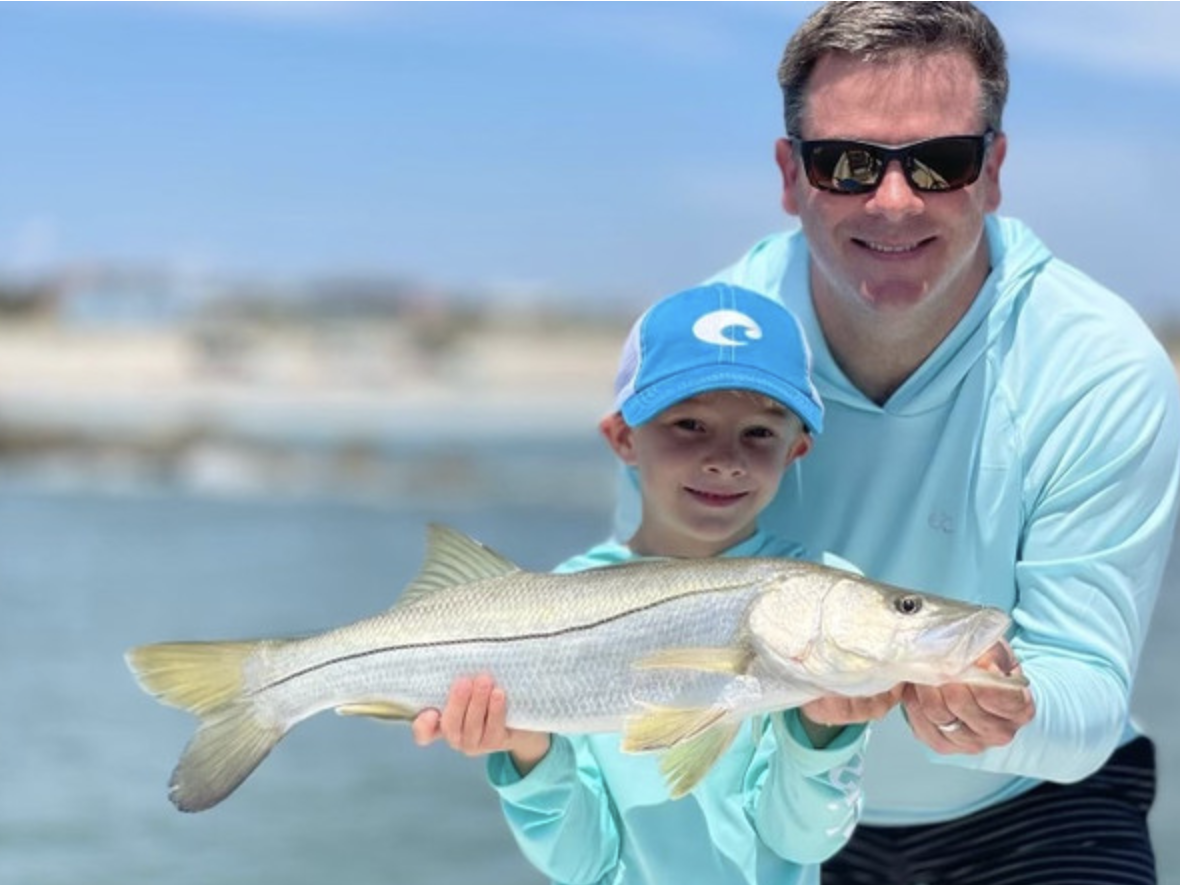 An uncle and nephew on an inshore fishing excursion in Florida, holding a caught-and-released snook.