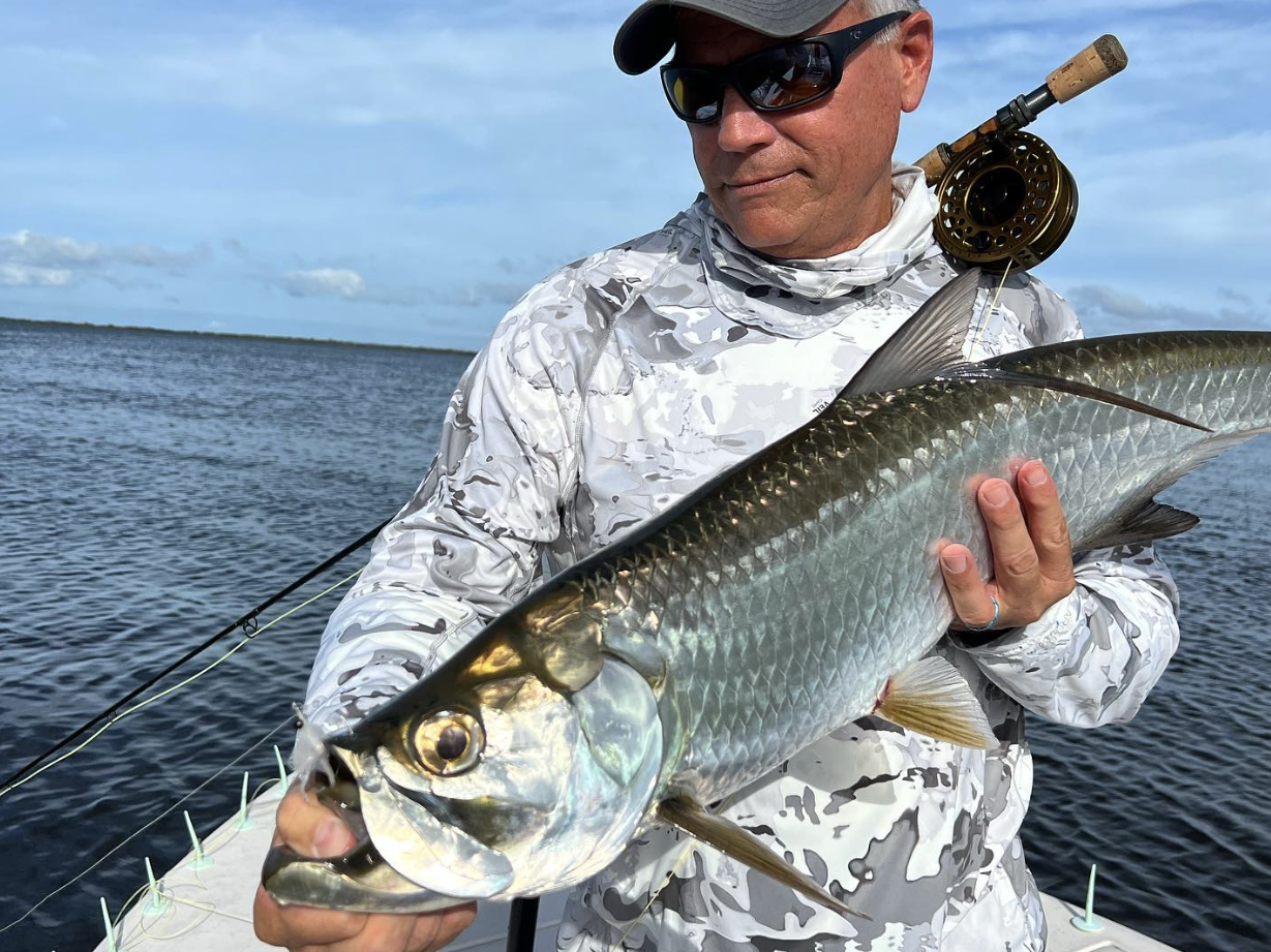 Client proudly holds up a tarpon catch during a fishing charter while fly fishing in the Florida Keys.