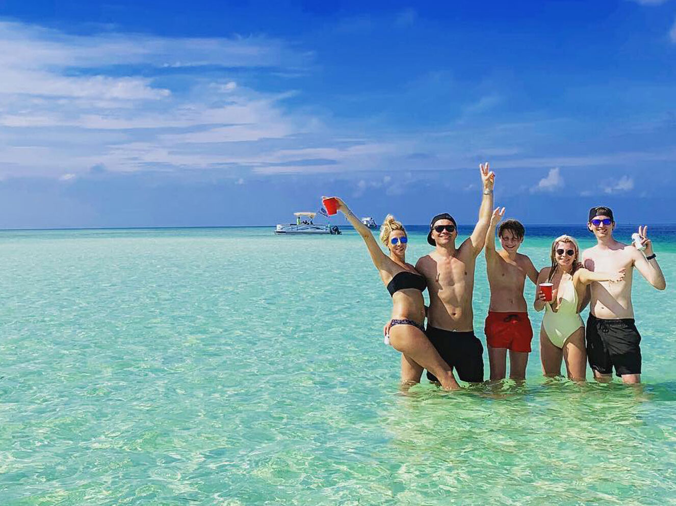 A group of friends enjoying a day at the sandbar in Florida during their vacation. They are on a sandbar charter, relaxing and socializing in the beautiful coastal setting.