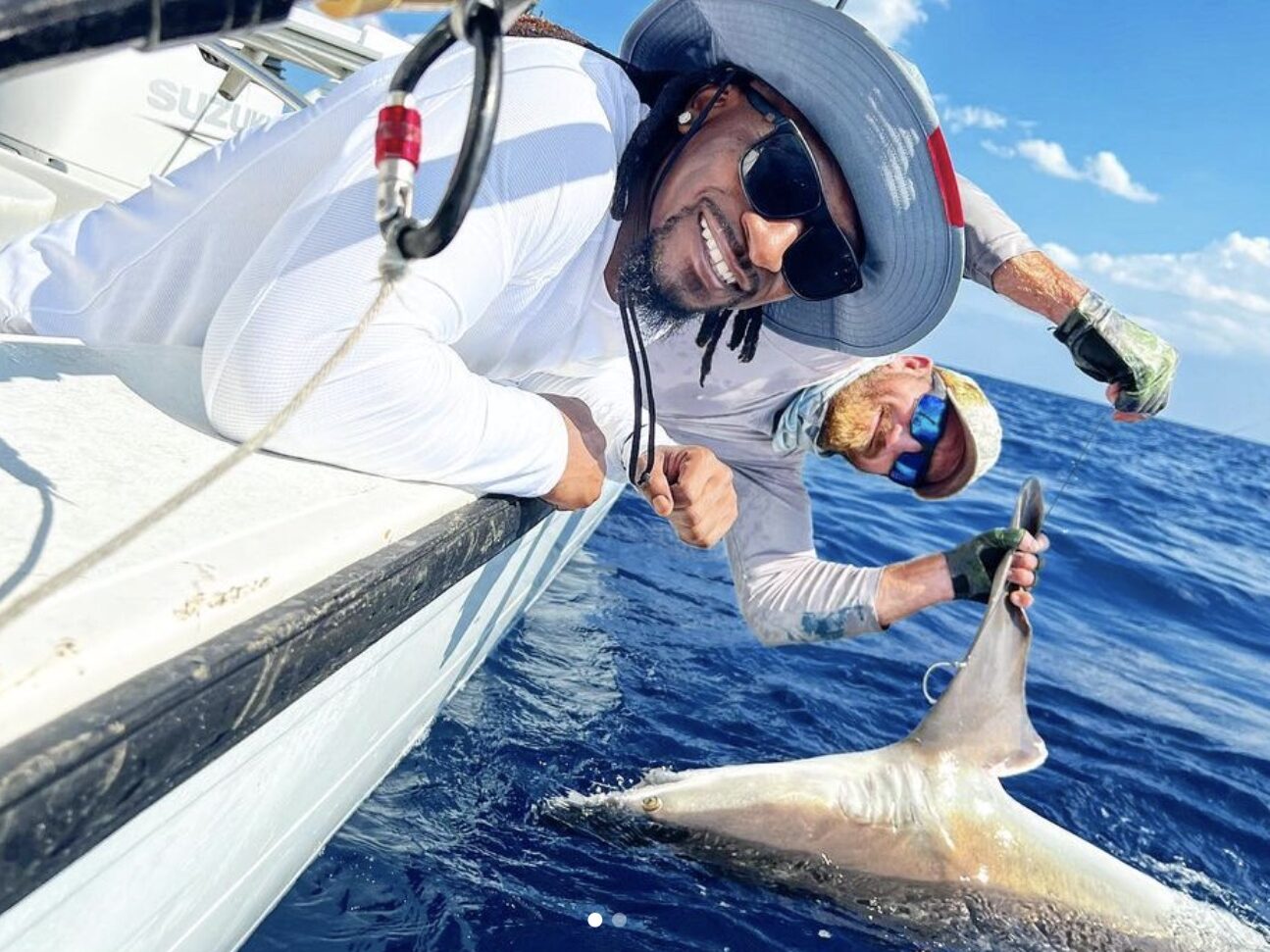 Captain and customer posing alongside boat after catching a shark on a fishing charter in Florida, emphasizing catch and release practices.