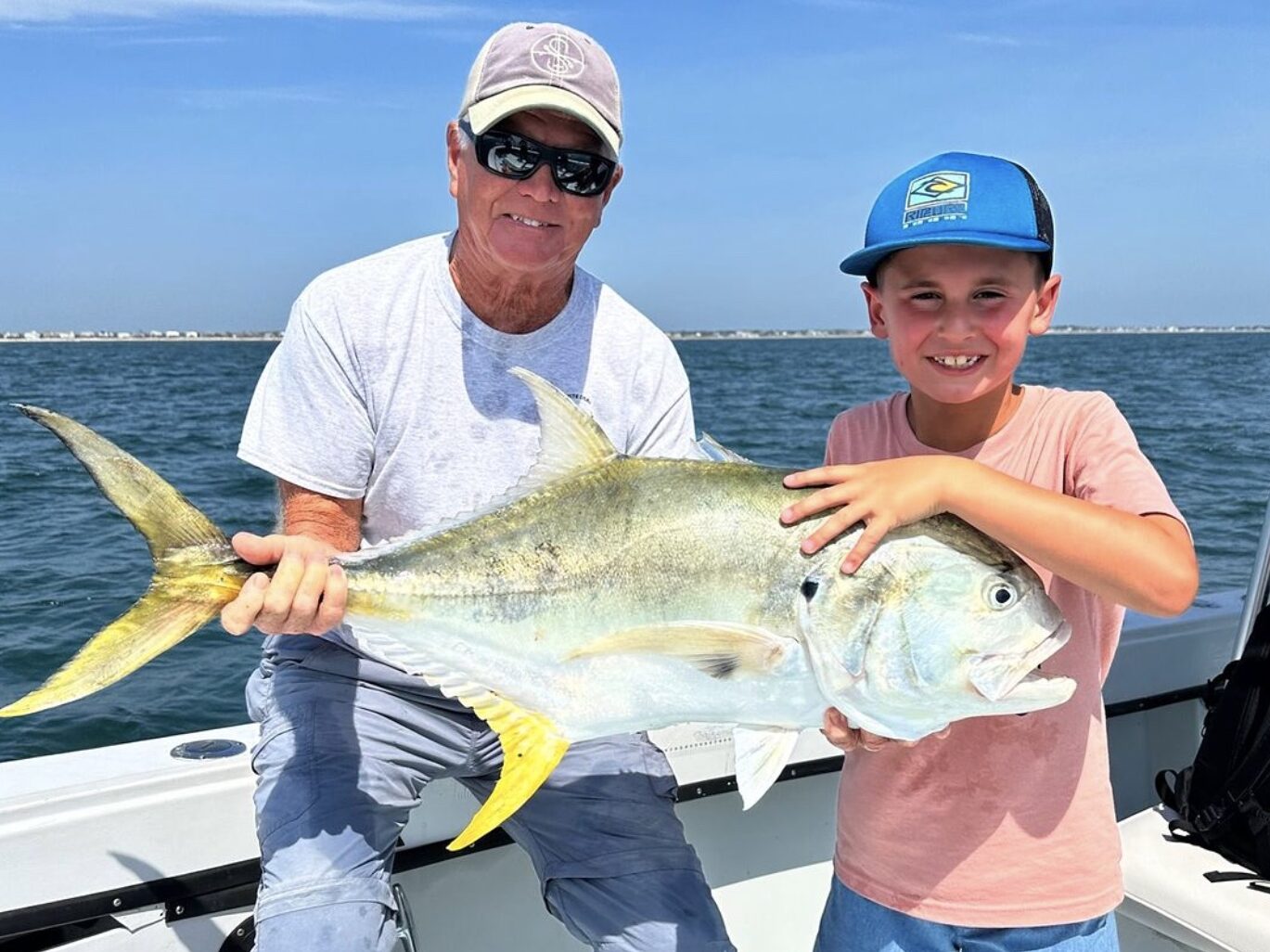 A father and son enjoying a family-friendly fishing trip in Florida. They are smiling while holding their catch, showcasing the bonding and excitement of fishing together on a memorable vacation.