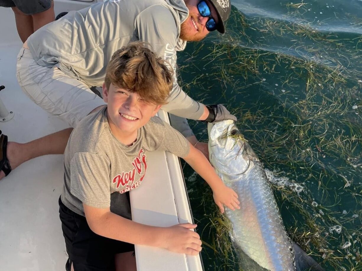 Charter Captain in Key West guiding a young client as they proudly hold up a tarpon during a family-friendly inshore fishing charter in the Florida Keys.