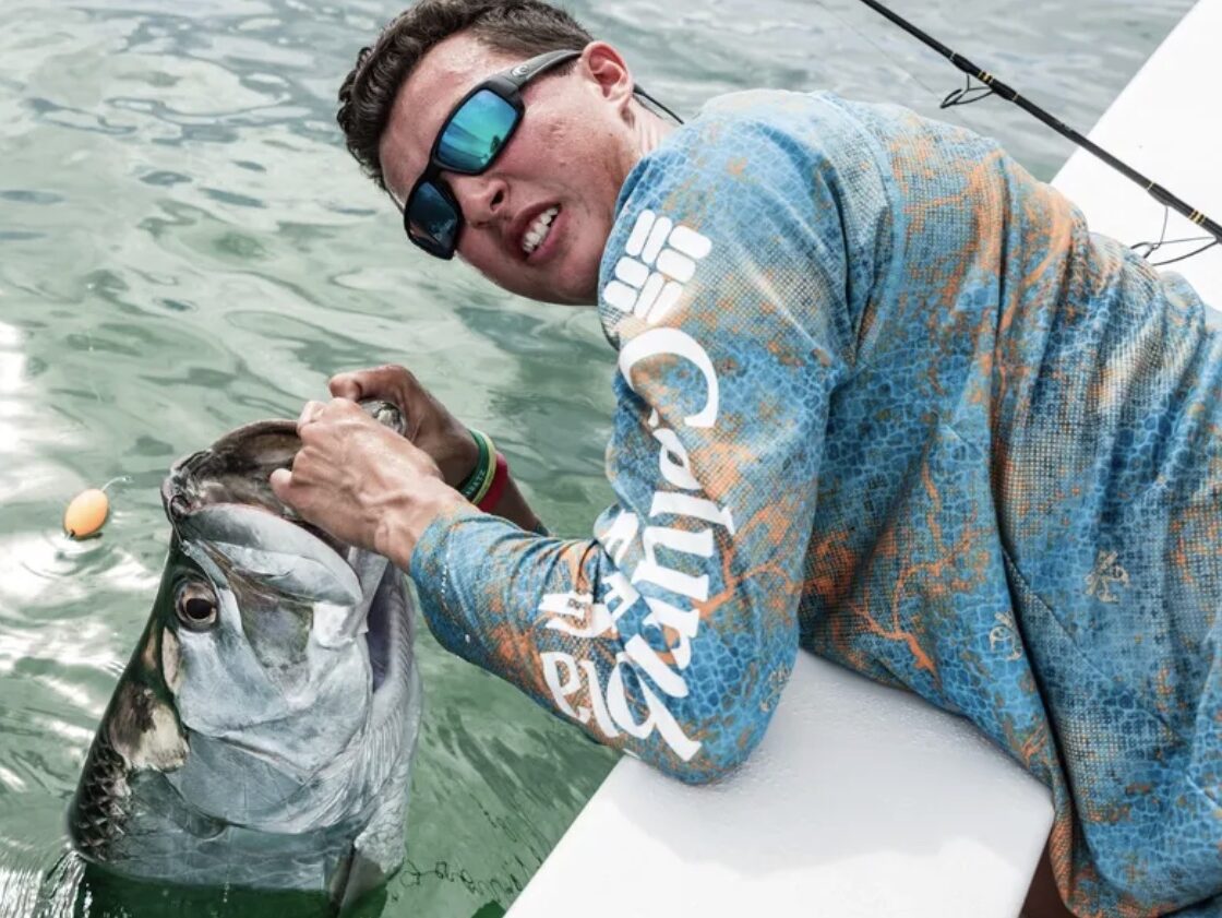 Client proudly holds up a tarpon catch during a catch-and-release tarpon charter in Fort Myers, enjoying a memorable day of fishing in the beautiful coastal waters.