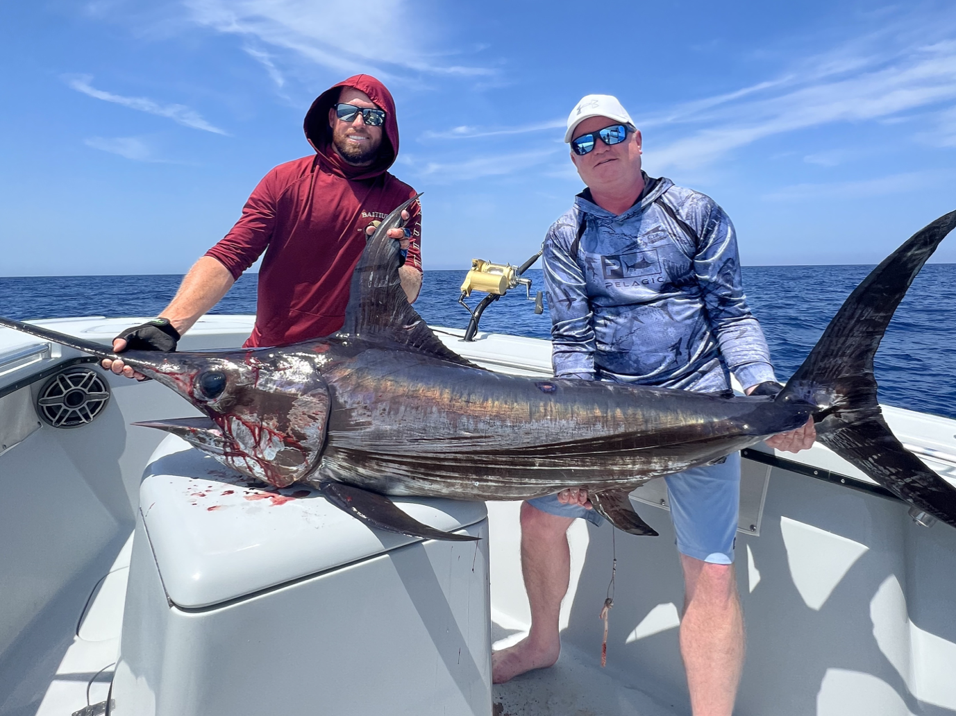 A charter captain and client proudly holding a swordfish catch while on a fishing charter in the Florida Keys, showcasing their successful and thrilling fishing experience in the beautiful coastal waters.