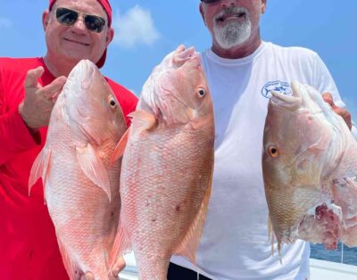 Two friends holding a mutton snapper partially eaten by a shark during a fishing charter in the Florida Keys.