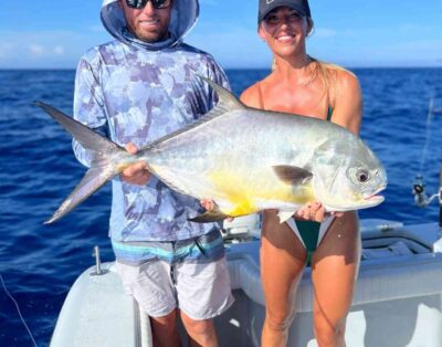 A couple holding a permit fish on a sunny day during a fishing charter.