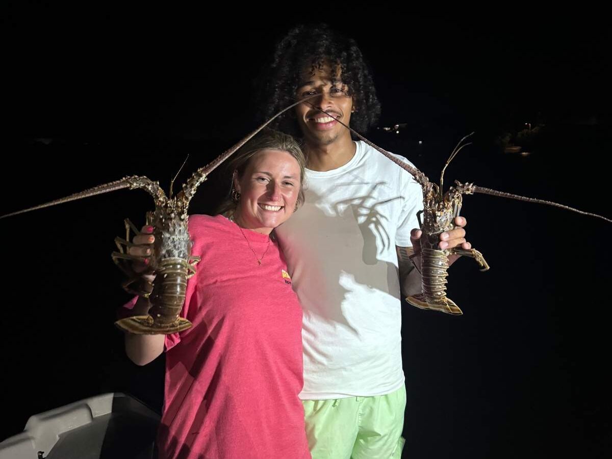 A happy couple holding up lobsters after a successful bully-netting charter in Key West, Florida.