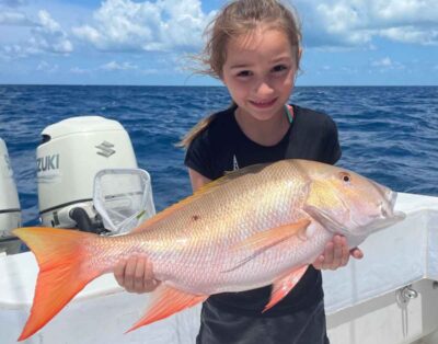 A young girl holding a mutton snapper during a family-friendly fishing charter in North Carolina's Outer Banks.