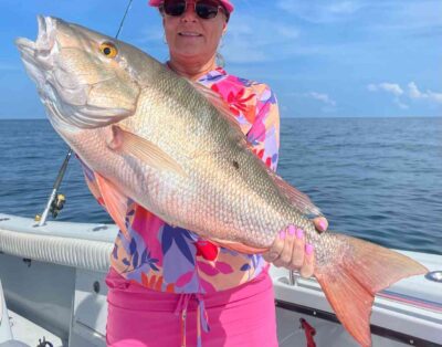 A woman proudly holding a giant mutton snapper caught while fishing key west wreck during a sunny day in Florida.