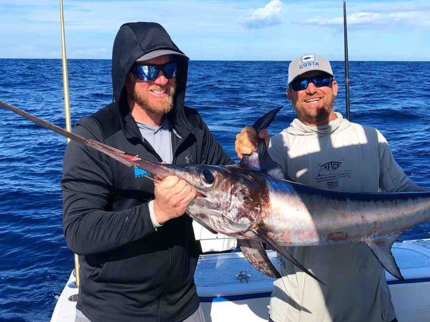 Captain and client holding a swordfish during a swordfishing charter in the Florida Keys.