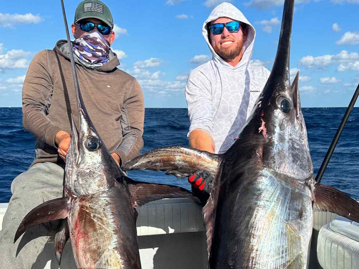 Two friends holding giant fish while on a swordfish charter in key west.