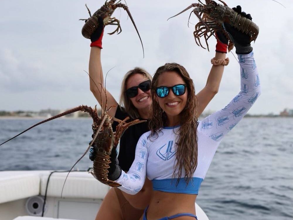 Two friends holding up lobsters caught during lobster fishing charter in Key West, Florida.