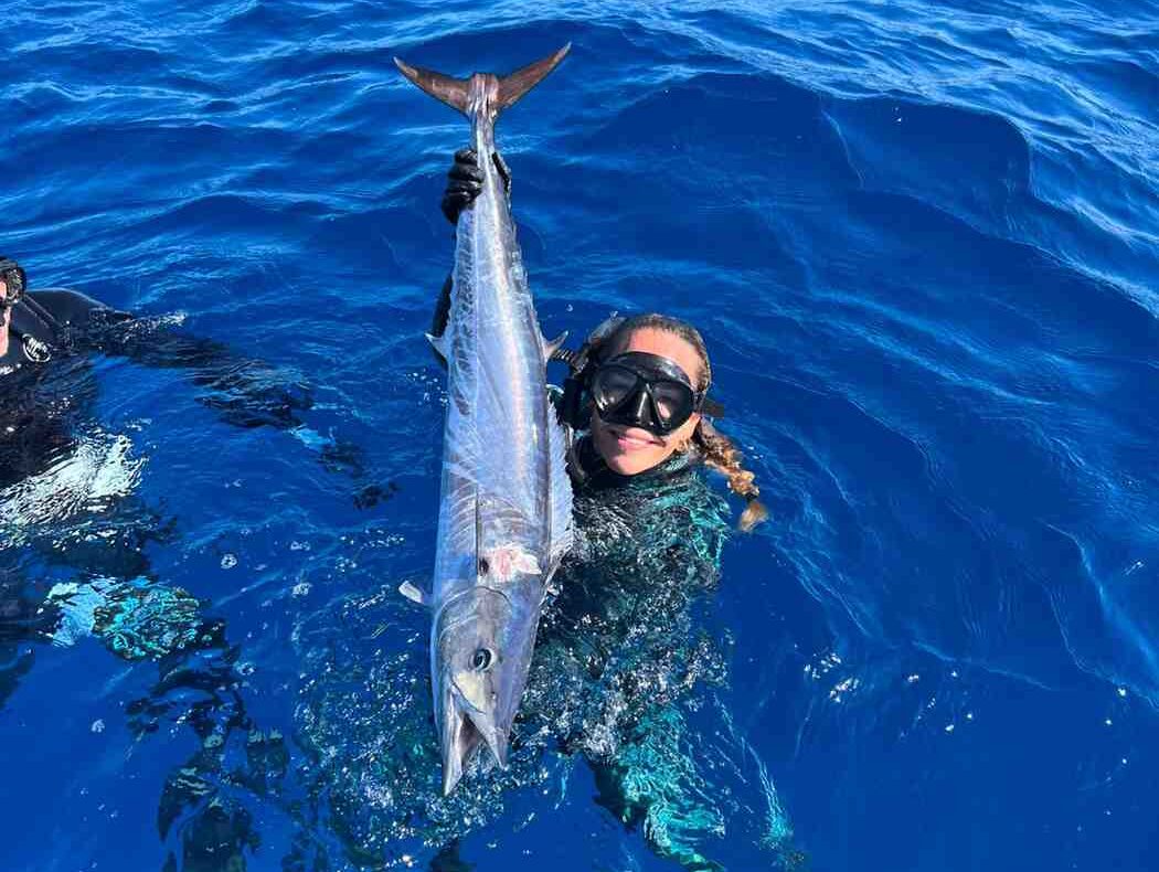 spearfishing girl wahoo fish e1758818079689 Reel Guides Nicole Steffens posing in water with wahoo fish after spearfishing.